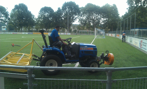 Na de brand: een voetbalveld wordt schoongemaakt.