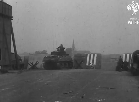 Opname gemaakt kort na de verovering van de Waalbrug door de geallieerdern. Een Britse tank wurmt zich tussen de betonnen versperringen door.